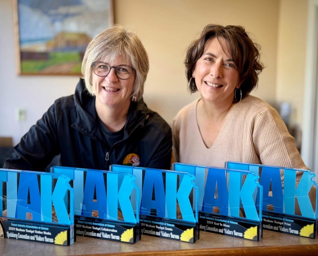 Two women with a row of awards.